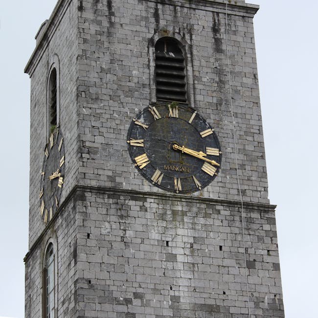A close-up view of the upper section of a historic stone clock tower showing two large round clocks with black faces and gold Roman numerals and clock hands. The primary clock, positioned centrally on the tower face, displays a time of approximately 3:16. The tower is constructed from gray stone blocks with a rough texture, some moss or weathering patches visible on surface. Above each clock, there are small arched louvered openings with dark slats. The photograph captures the tower against a cloudy, overcast sky, emphasizing the aged stonework and classic design of the clock face. In a context related to rubbish removal or on-site clearance, such a structure might be nearby, suggesting a historic building or public space. Rubbish Clearance Harringay may be involved in maintaining or providing disposal services for similar types of historic or large public structures, supporting private waste removal solutions beyond authority-led recycling channels. The overall scene highlights the architectural features of a traditional clock tower, with the focus on durability, functionality, and the passage of time, subtly connecting to the broader theme of building maintenance and waste management.